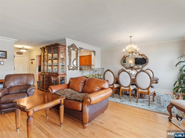 living room featuring light wood-type flooring, an inviting chandelier, baseboards, and crown molding