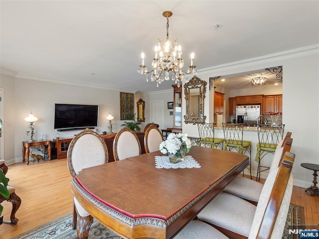 dining space with light wood finished floors, baseboards, ornamental molding, and a notable chandelier