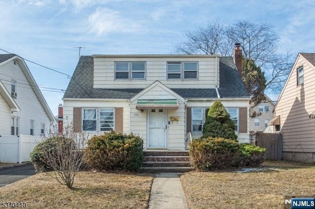 bungalow-style home featuring roof with shingles, fence, and a chimney