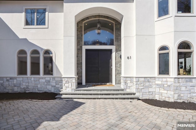 property entrance with stone siding and stucco siding