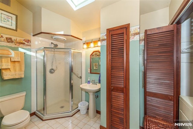 bathroom featuring toilet, a skylight, a sink, visible vents, and a shower stall