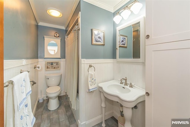 full bathroom featuring toilet, a wainscoted wall, and crown molding