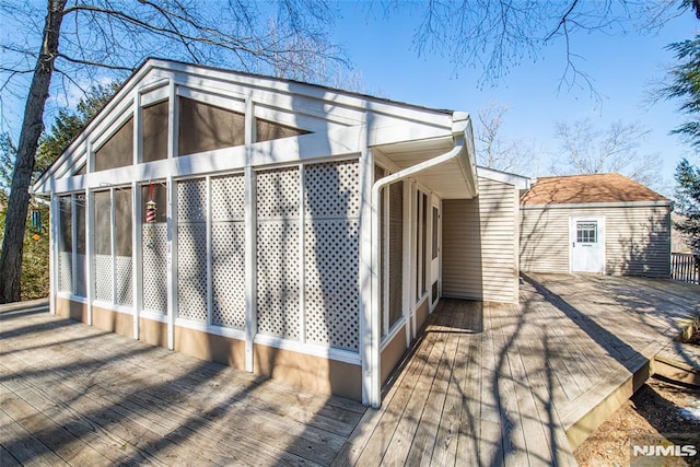 view of property exterior featuring a sunroom and a wooden deck