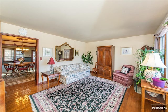 living room with a wealth of natural light, wood finished floors, and an inviting chandelier