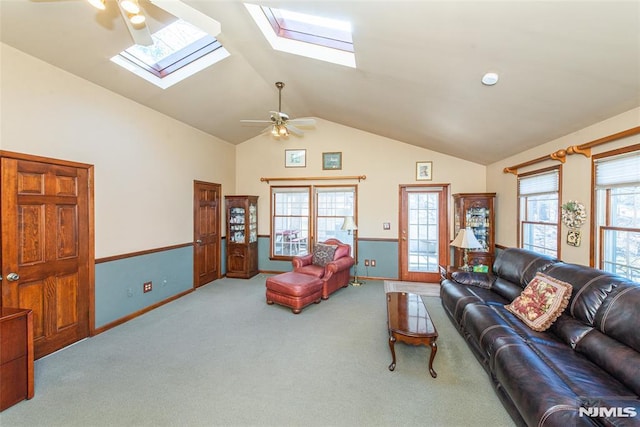 living room with lofted ceiling with skylight, carpet flooring, baseboards, and a ceiling fan