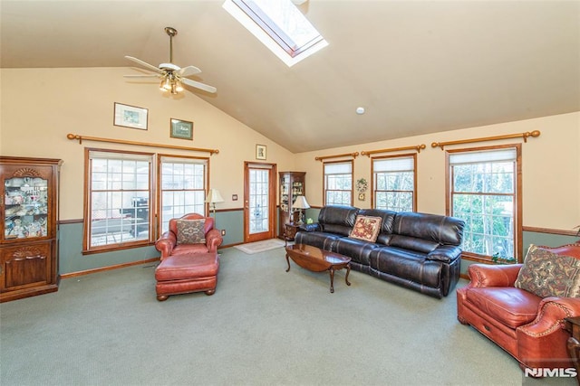 carpeted living room with a healthy amount of sunlight, a skylight, baseboards, and high vaulted ceiling