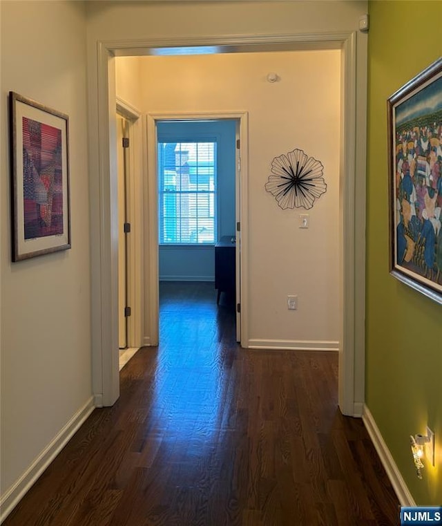 hallway featuring dark wood-style floors and baseboards