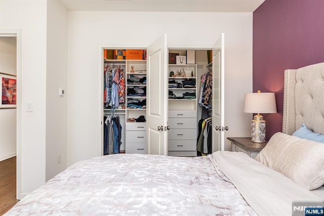 bedroom with a spacious closet and wood finished floors