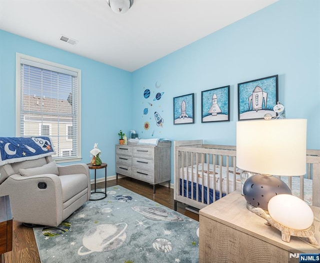 bedroom featuring wood finished floors, visible vents, and baseboards