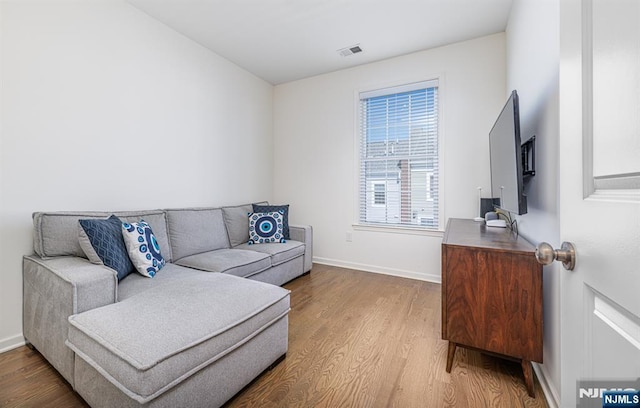 living room with visible vents, baseboards, and wood finished floors