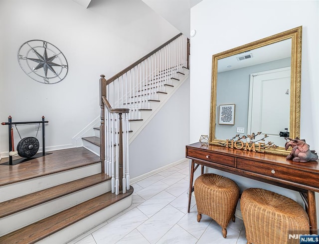 stairway with baseboards, visible vents, and marble finish floor