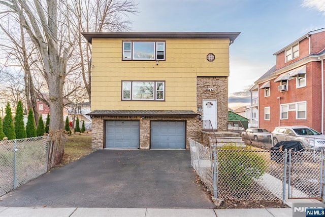 view of front of house with a fenced front yard, brick siding, a garage, and aphalt driveway