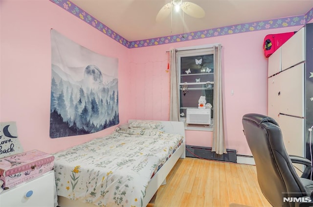 bedroom featuring ceiling fan, baseboard heating, and wood finished floors