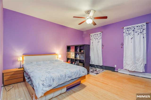 bedroom featuring ceiling fan, a baseboard radiator, and wood finished floors