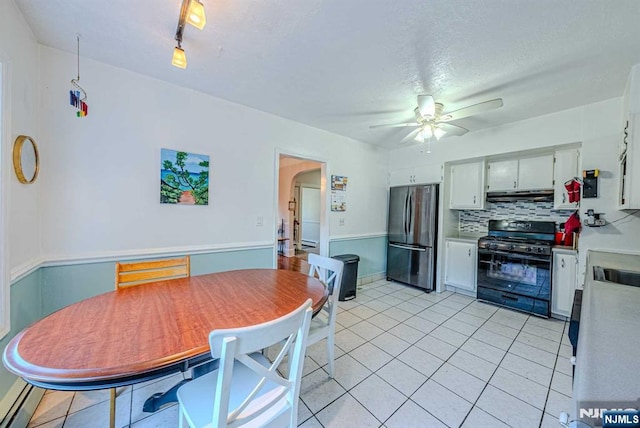 kitchen featuring arched walkways, decorative backsplash, freestanding refrigerator, under cabinet range hood, and gas stove