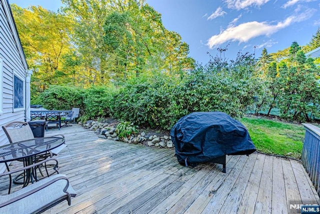 wooden terrace featuring outdoor dining space and grilling area