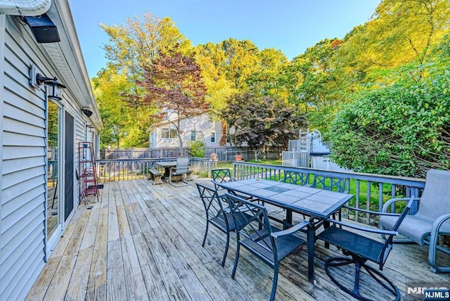 wooden terrace featuring outdoor dining area and a fenced backyard