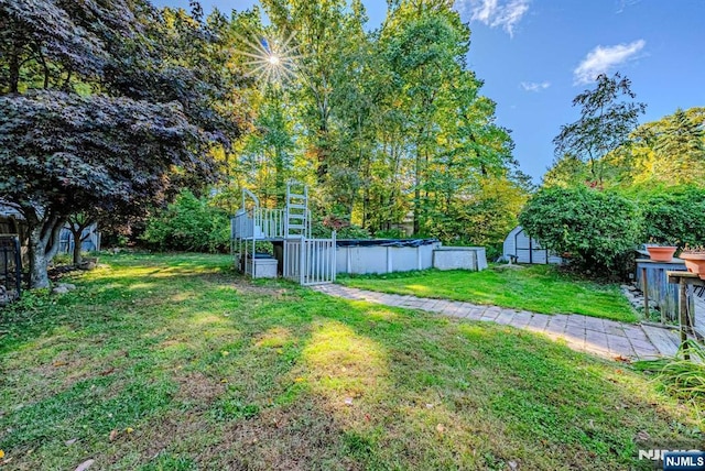 view of yard featuring an outbuilding, an outdoor pool, and a storage shed