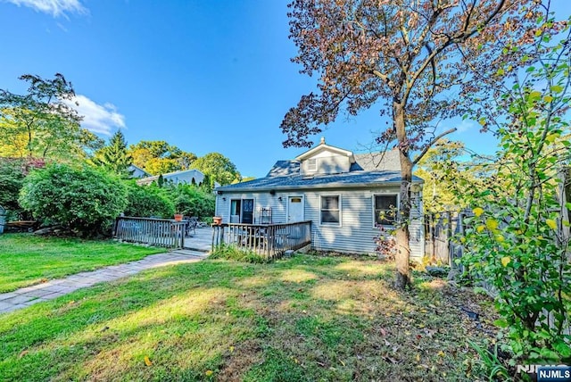 view of front of property featuring fence, a wooden deck, and a front lawn