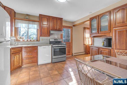 kitchen with a baseboard heating unit, plenty of natural light, stainless steel range with gas stovetop, and white dishwasher