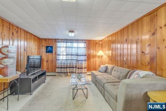 living room featuring a baseboard heating unit, wood walls, and carpet