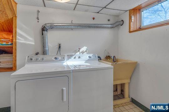 clothes washing area featuring baseboards, a sink, and washing machine and clothes dryer