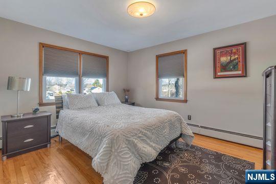 bedroom with a baseboard heating unit, baseboard heating, and light wood-type flooring