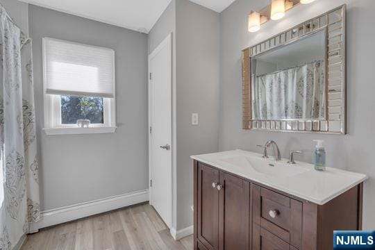 full bathroom with curtained shower, baseboards, wood finished floors, and vanity