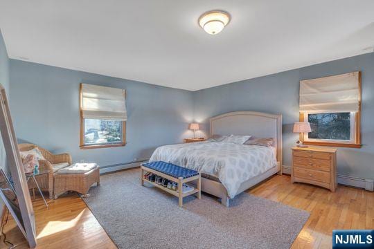 bedroom with baseboard heating, wood finished floors, and baseboards