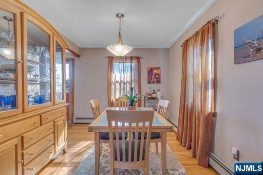 dining space featuring a baseboard heating unit and light wood finished floors