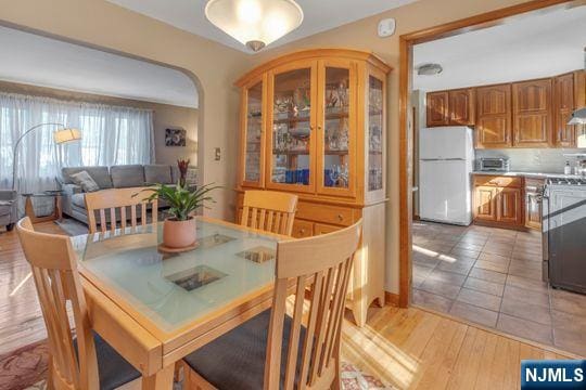 dining room with arched walkways and light wood-style flooring