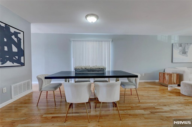 dining space featuring light wood finished floors, visible vents, and baseboards