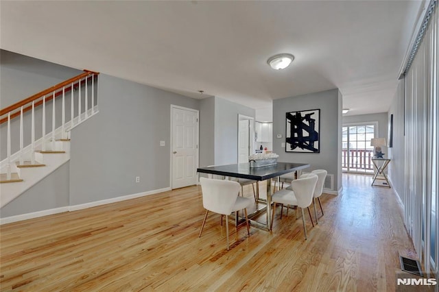 dining area with light wood-style floors, baseboards, stairs, and visible vents