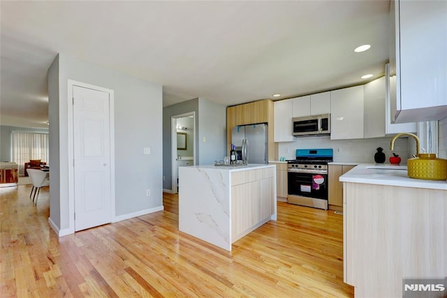 kitchen featuring light wood-style flooring, decorative backsplash, appliances with stainless steel finishes, a sink, and a kitchen island