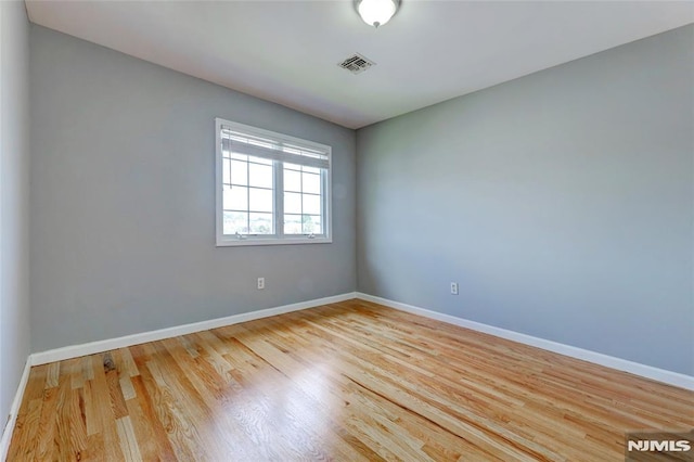 unfurnished room with wood finished floors, visible vents, and baseboards