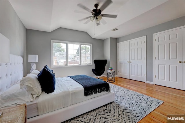 bedroom featuring baseboards, visible vents, a ceiling fan, lofted ceiling, and wood finished floors