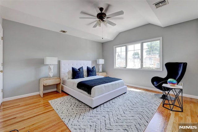 bedroom featuring lofted ceiling, wood finished floors, visible vents, and baseboards