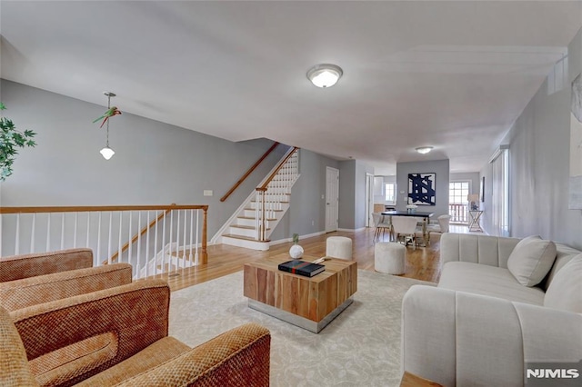 living room featuring stairway, baseboards, and wood finished floors