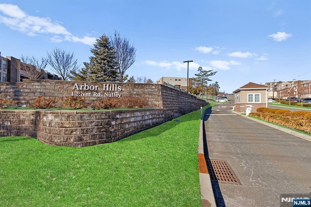 community / neighborhood sign featuring a residential view and a lawn