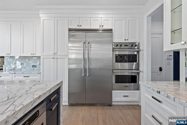 kitchen featuring glass insert cabinets, light wood-style flooring, appliances with stainless steel finishes, and white cabinets