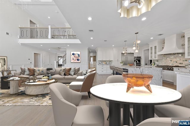 dining space with recessed lighting, light wood-type flooring, visible vents, and a decorative wall