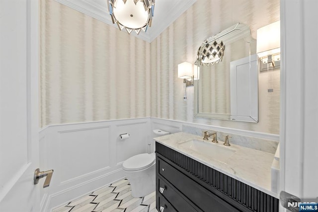 half bathroom with toilet, a wainscoted wall, crown molding, vanity, and a decorative wall