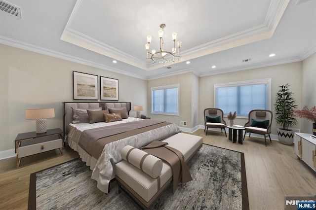 bedroom featuring a chandelier, visible vents, a raised ceiling, and light wood-style flooring