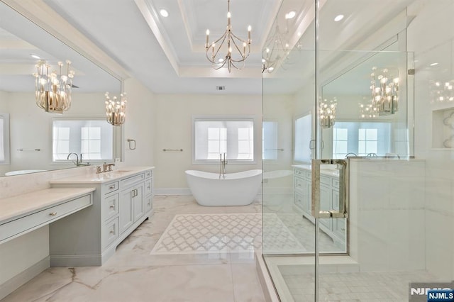 bathroom featuring a chandelier, a tray ceiling, a freestanding tub, and a wealth of natural light