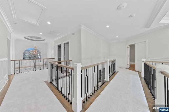 hallway featuring visible vents, ornamental molding, attic access, an upstairs landing, and wood finished floors