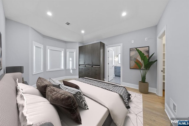 bedroom featuring light wood finished floors, recessed lighting, visible vents, ensuite bath, and baseboards