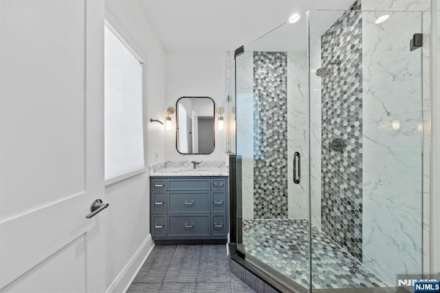 full bath with a stall shower, vanity, and baseboards