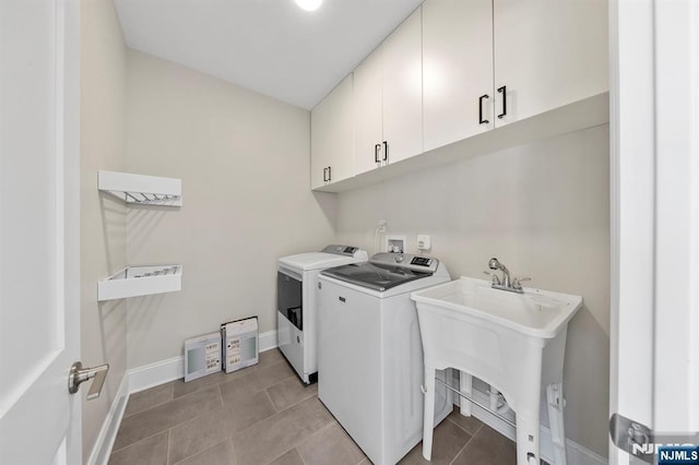 laundry area featuring cabinet space, light tile patterned floors, baseboards, washing machine and clothes dryer, and a sink