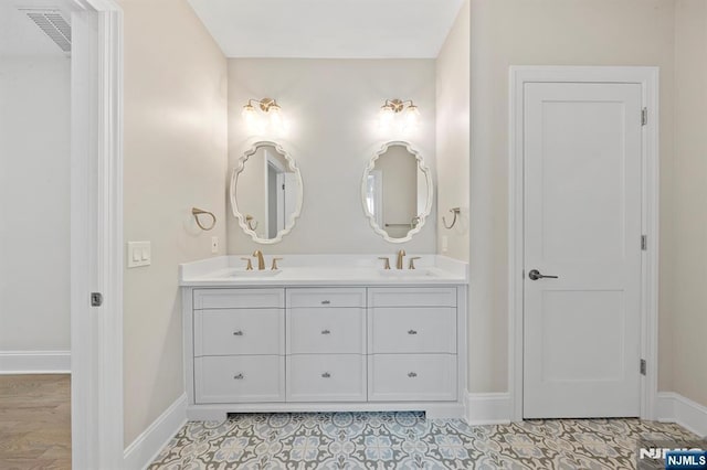 full bath featuring double vanity, baseboards, visible vents, and a sink