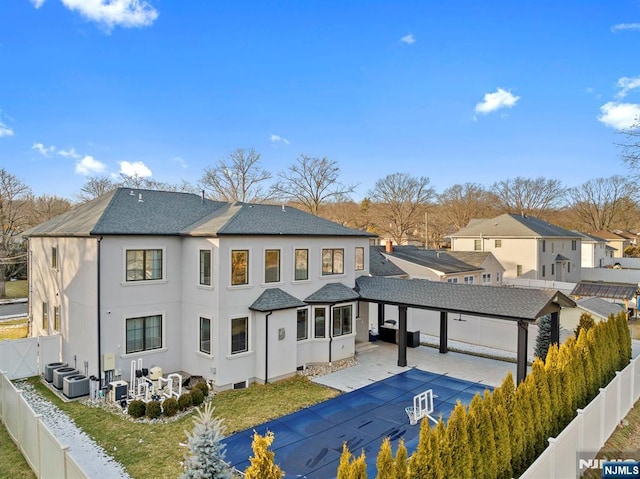 rear view of property featuring a fenced backyard, concrete driveway, and a patio